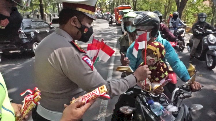 Kasat Lantas Polres Demak, AKP Fandy Setiawan, bagikan bendera dan coklat ke pengendara, usai detik detik proklamasi.