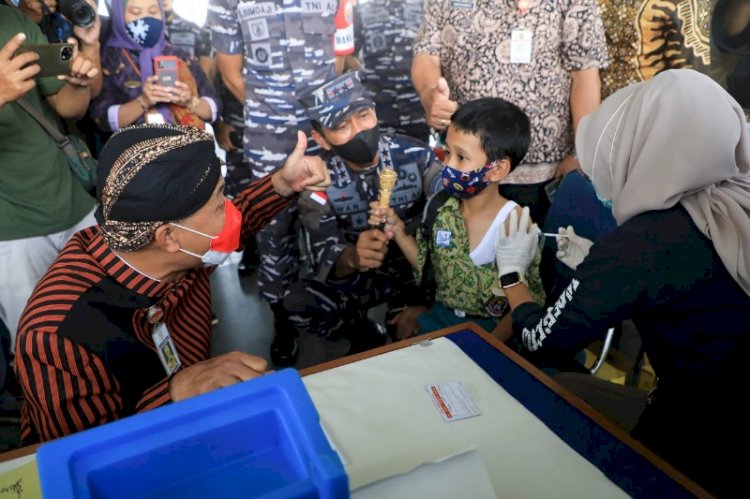 Gubernur Jateng Ganjar Pranowo dan Pangkoarmada II Laksda TNI Iwan Isnurwanto, saat menenangkan seorang anak yang takut disuntik, dalam vaksinasi di atas kapal perang, Kamis (6/1). foto: jatengprov.go.id. .
