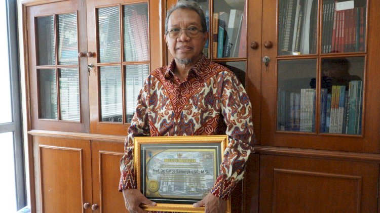 Prof. Dr. Gatot Sasongko, S.E., M.S., menunjukkan penghargaan yang ia terima.