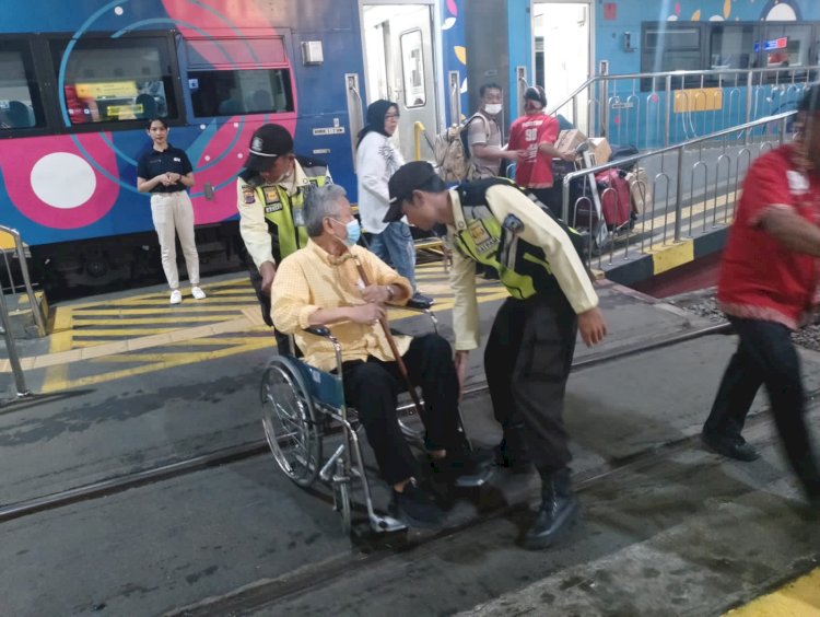 Penumpang kereta api penyandang disabilitas yang dibantu petugas untuk naik ke dalam kereta