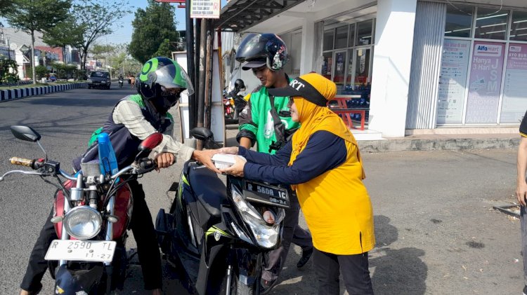 Salah seorang alumni SMAN 1 Purbalingga saat membagikan nasi bungkus kepada warga masyarakat.