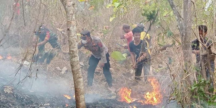 Masyarakat bersama anggota polisi berusaha memadamkan api yang membakar bukit. Dok