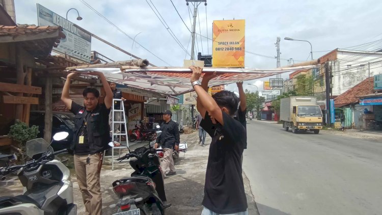 Petugas Bawaslu, menurunkan APK yang masih terpasang di masa tenang, Minggu (11/2) siang. Rubadi/Dok.RMOLJateng